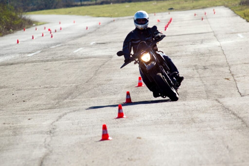 Motocyklista ćwiczy slalom, aby zdobyć prawo jazdy A2.