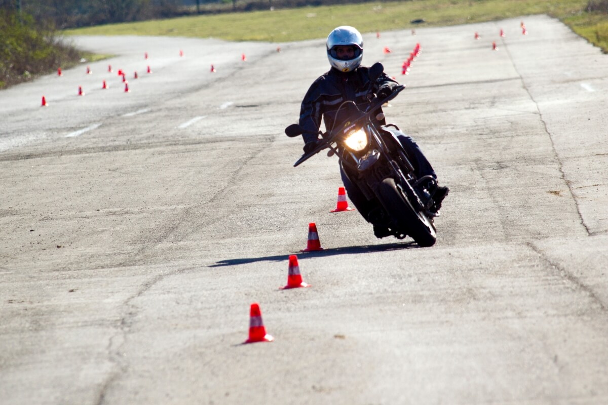 Motocyklista ćwiczy slalom, aby zdobyć prawo jazdy A2.