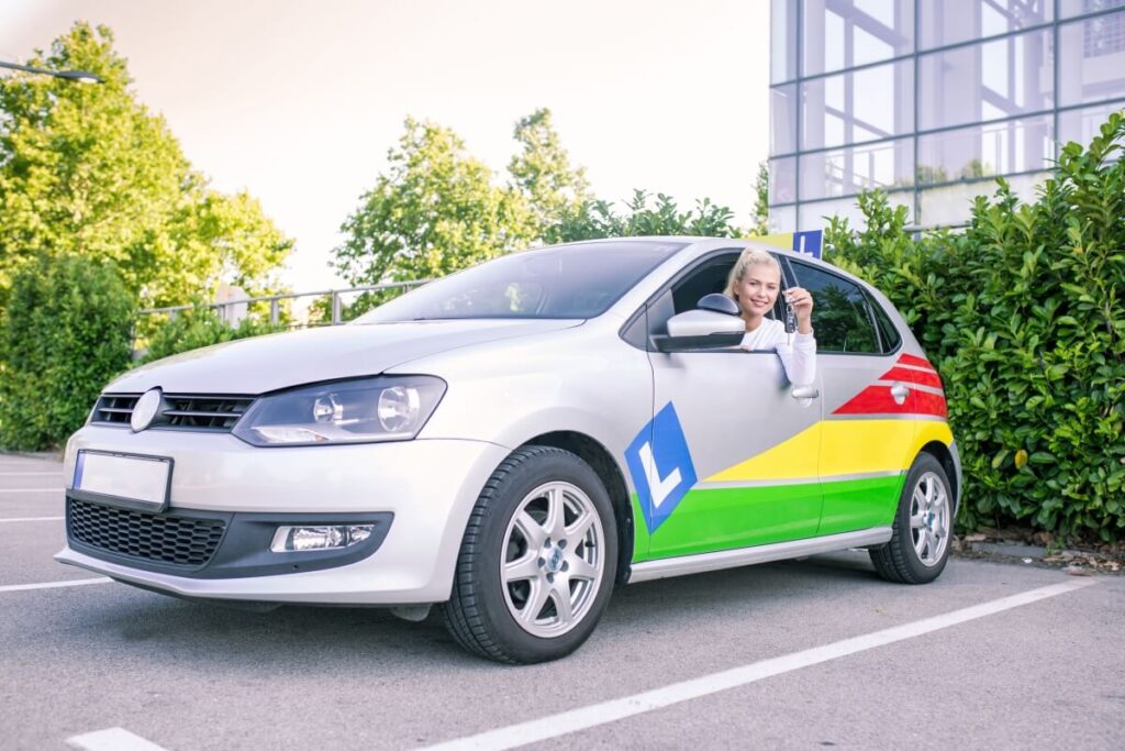 Kursantka w aucie nauki jazdy trzyma kluczyki, rozważając zmianę szkoły jazdy w trakcie kursu